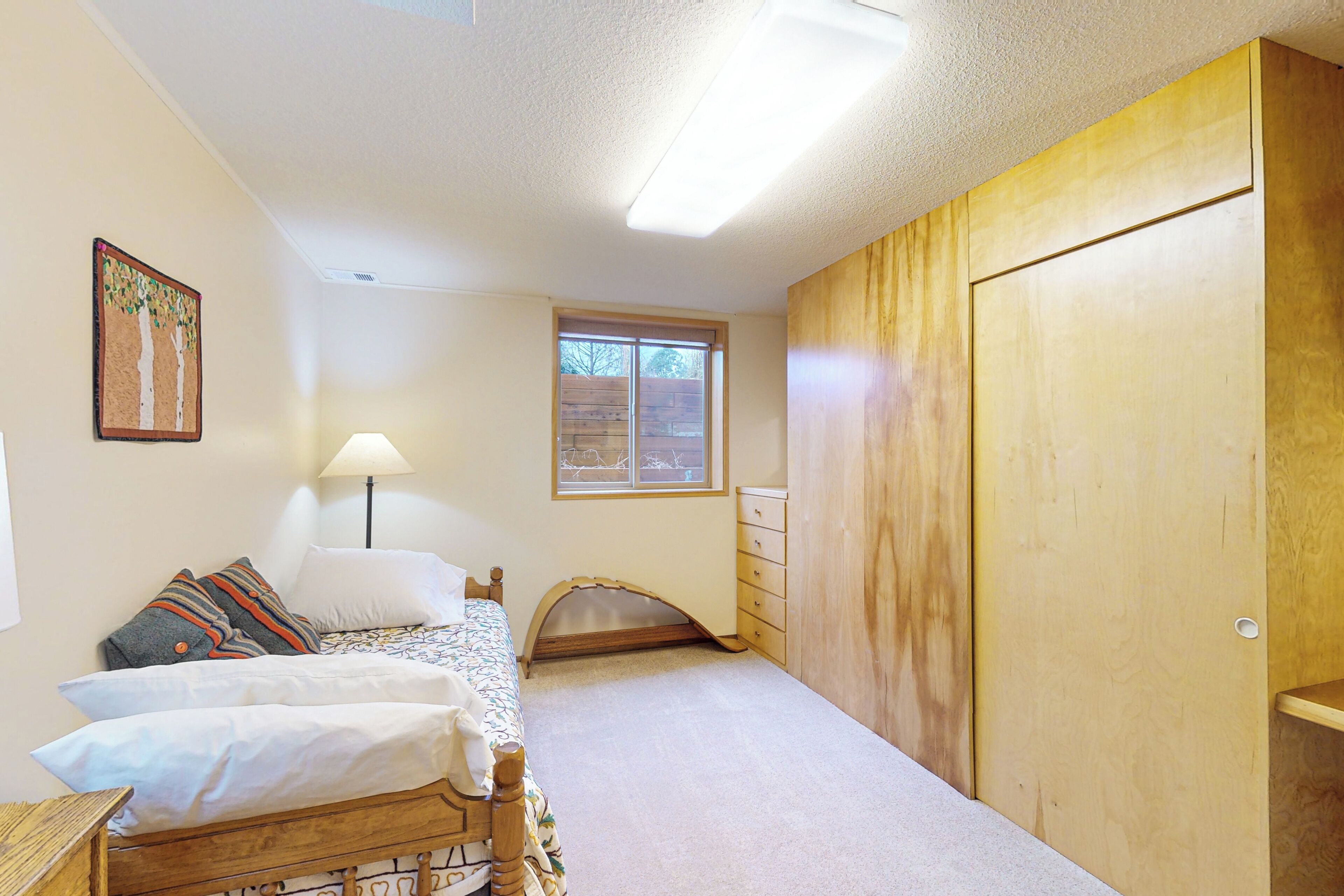A bedroom with a bed, a dresser, a window, and a door.