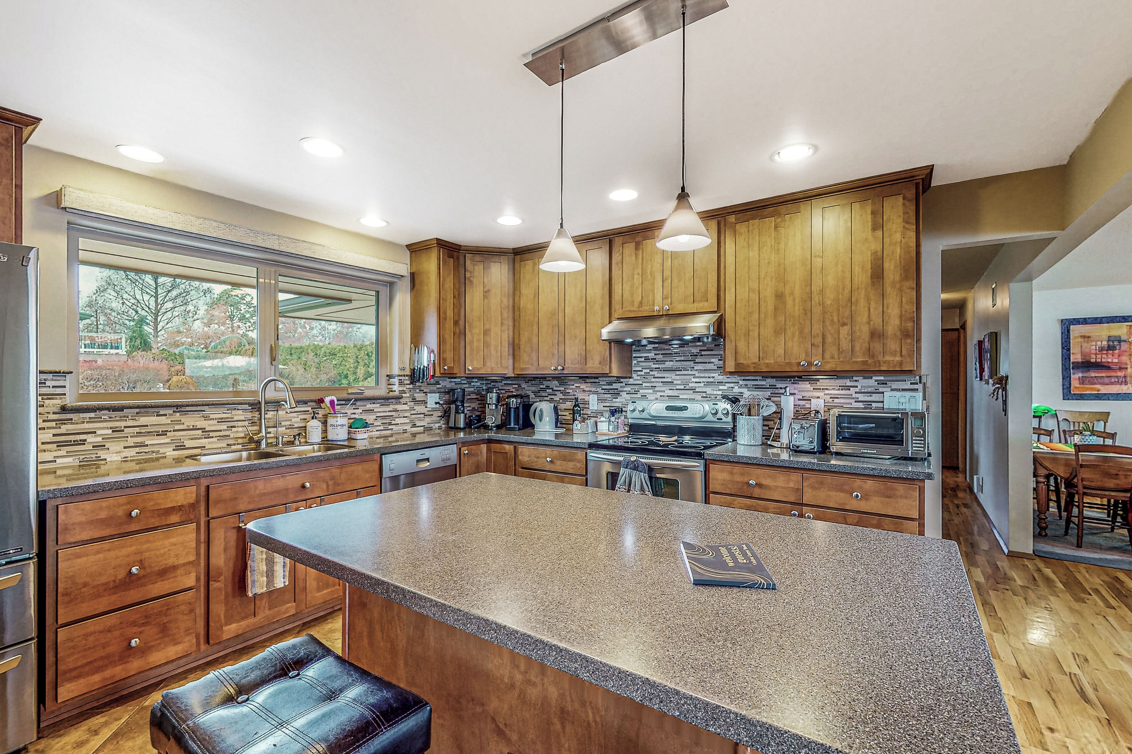 A modern kitchen with granite countertops, wooden cabinets, and stainless steel appliances.