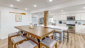 A modern kitchen with white cabinets, a wooden dining table, and bar stools. - Private Dock! Dog-friendly Lake Livingston Retreat (Pointblank)