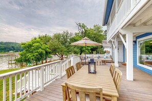 A wooden deck with a table and chairs, overlooking a body of water, with a white railing and a covered seating area. - Private Dock! Dog-friendly Lake Livingston Retreat (Pointblank)