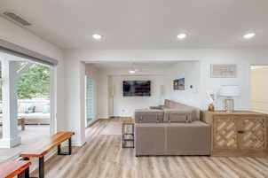 Uma sala de estar moderna com um sofá, um banco de madeira e uma mesinha lateral.