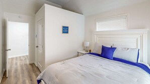 A bedroom with a bed, a nightstand, a wall-mounted lamp, and a door. - Private Dock! Dog-friendly Lake Livingston Retreat (Pointblank)