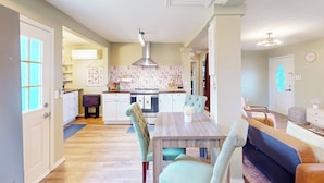 A modern kitchen with a central island, a dining area with a wooden table and chairs, and a living room with a sofa and a coffee table.