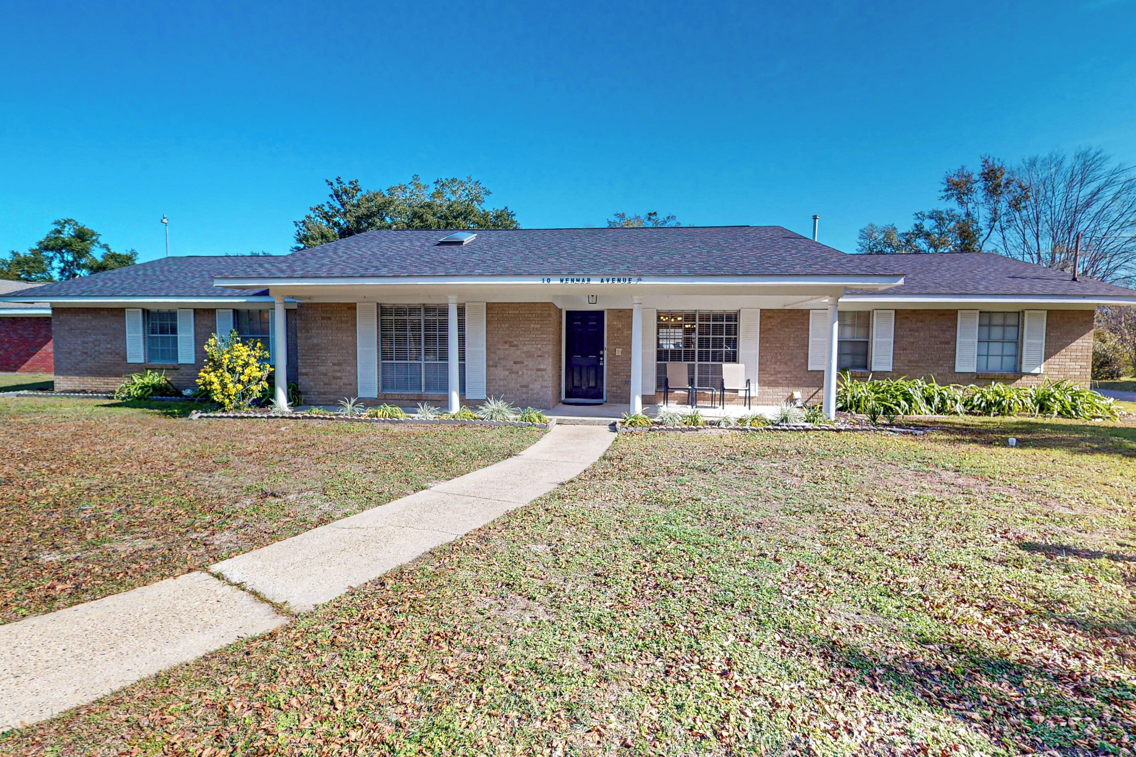 A two-story house with a front porch, brick exterior, and a clear sky.