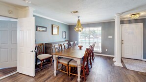 A dining room with a wooden table and chairs, a chandelier, and a view through the window. - Poolside Bliss! Christian Pass Family Home w/ Yard (Pass Christian)