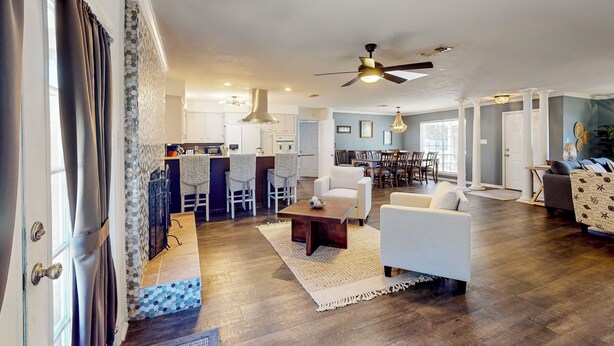 A spacious living room with a large ceiling fan, a dining area with a kitchen in the background, and a cozy seating area with a patterned rug. - Poolside Bliss! Christian Pass Family Home w/ Yard (Pass Christian)