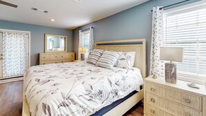 A bedroom with a bed, dresser, mirror, and window with blinds. - Poolside Bliss! Christian Pass Family Home w/ Yard (Pass Christian)
