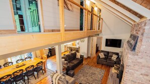 Un loft espacioso con comedor, dos sofás, una alfombra grande y una pared de ladrillo.