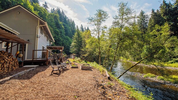 Una cabaña con terraza, mobiliario exterior y vista al río.
