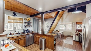 A modern kitchen with wooden accents, a central island, and a dining area with a view of the outdoors. - Fire Pit! A-frame Escape, 33 Mi to Sunrise Park (Pinetop)