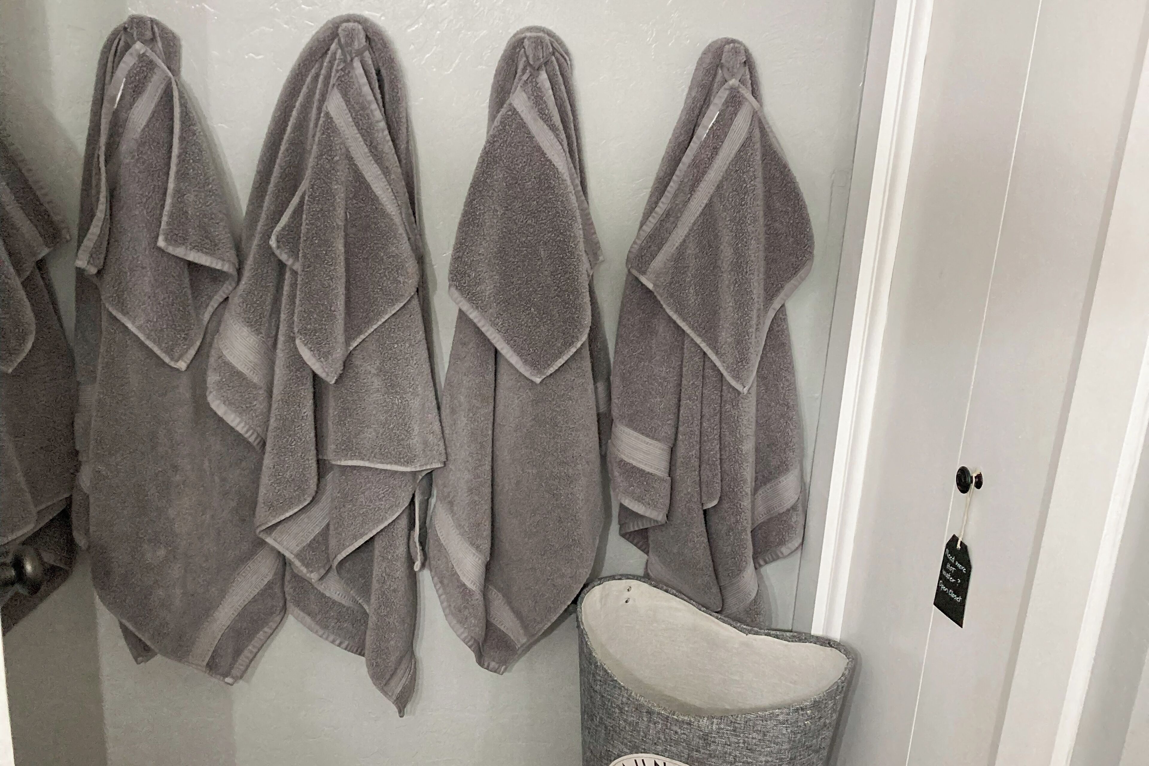 A bathroom with four towels hanging on a rack and a white door with a black tag.