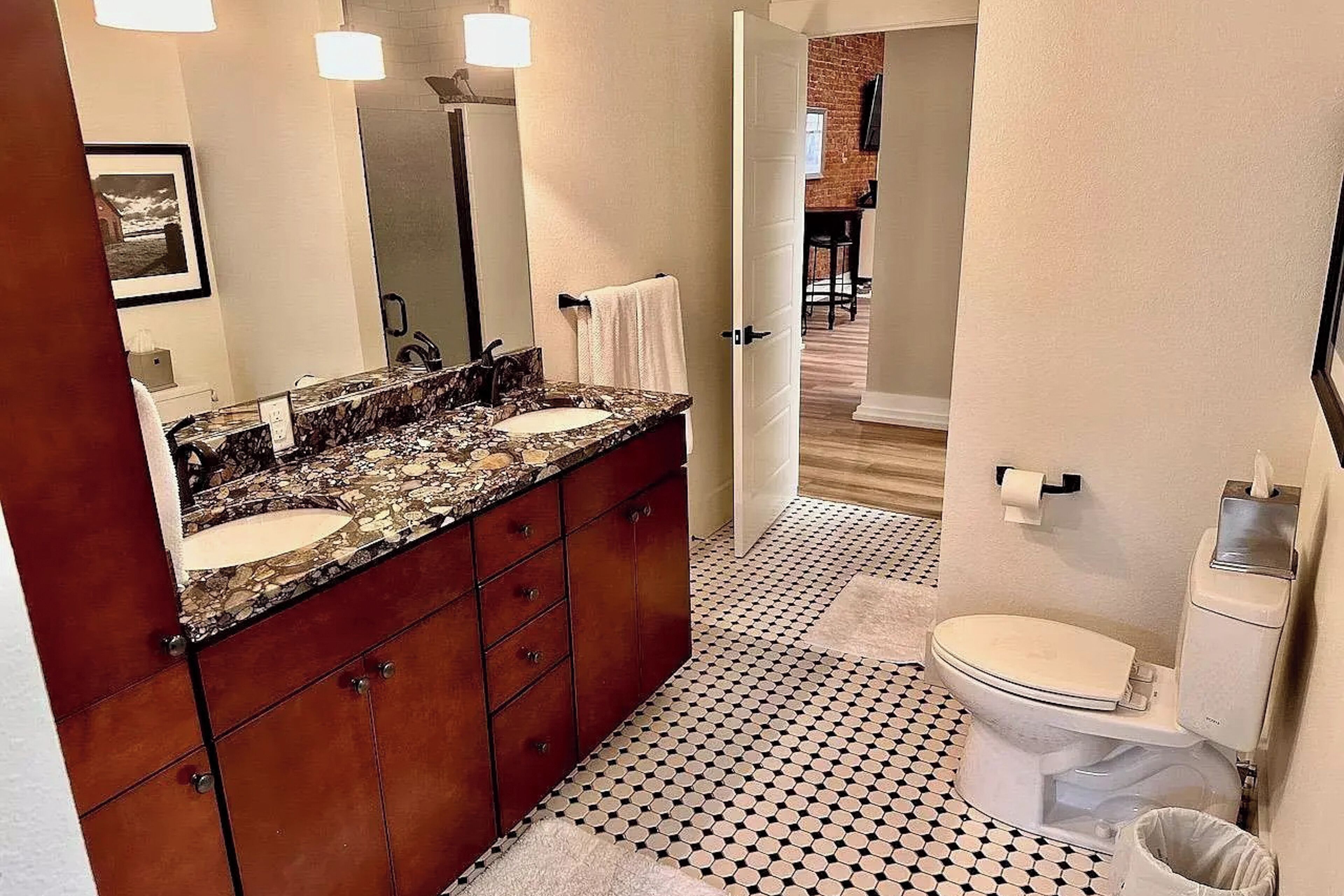A bathroom with a double sink vanity, a toilet, and a patterned floor.