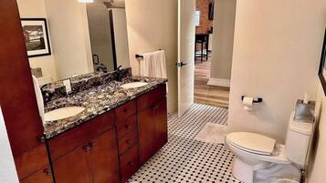 A bathroom with a double sink vanity, a toilet, and a patterned floor.