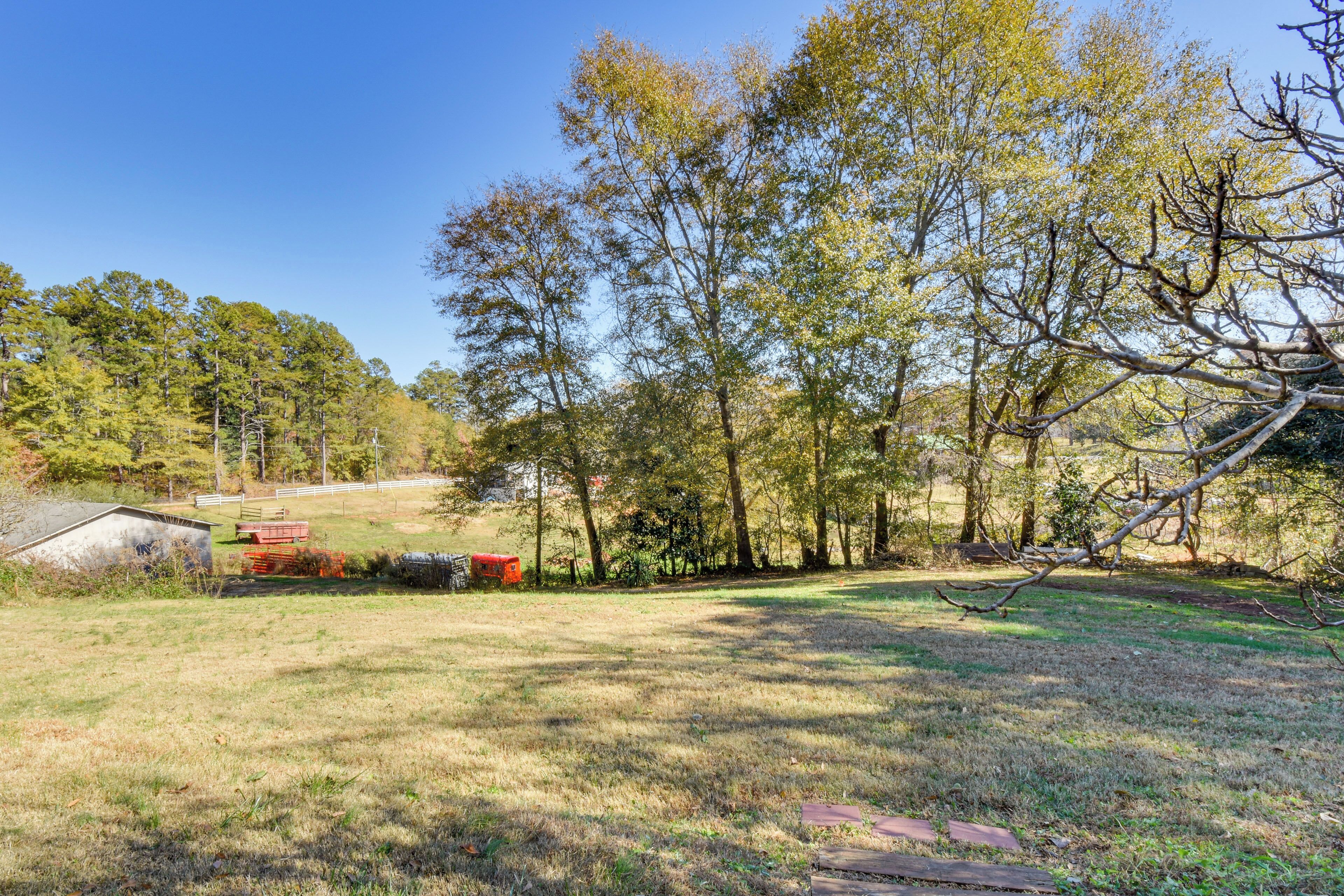 A rural landscape with a grassy field, trees, and a small shed.