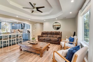 A spacious living area with a brown leather sofa, wooden coffee table, and a dining area with blue cabinets and a kitchen in the background. - 4 Seasons of Fun! Walhalla Home w/ Spacious Yard! (Walhalla)