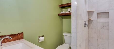 A bathroom with a sink, toilet, and shower area.