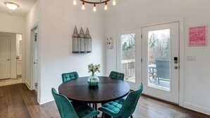 A dining area with a round table, four teal chairs, a vase with flowers, and a chandelier. - Hot Tub & Yard: 'temptation Stays' Home in Roanoke (Roanoke)