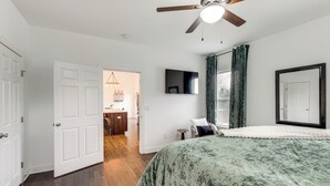 A bedroom with a bed, a ceiling fan, a TV, and a door leading to another room. - Hot Tub & Yard: 'temptation Stays' Home in Roanoke (Roanoke)