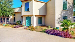 Une maison à deux étages, avec une façade de couleur beige, une porte verte et un petit balcon.