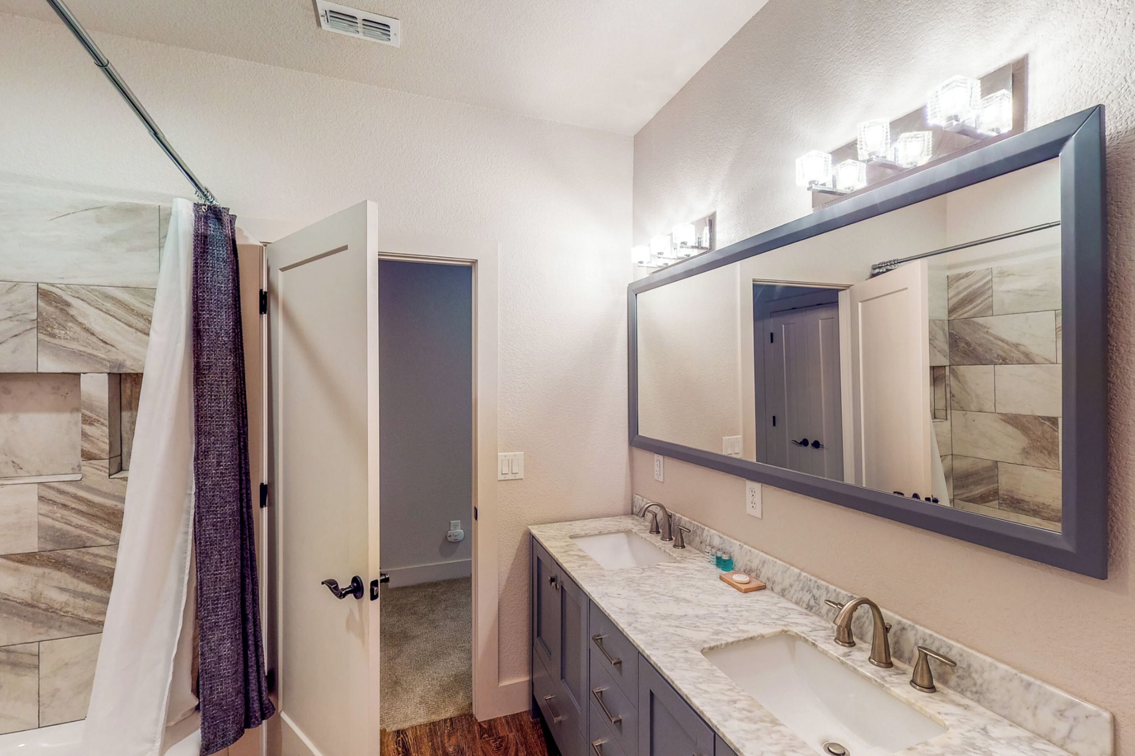 A bathroom with a large mirror, a sink, and a shower curtain.