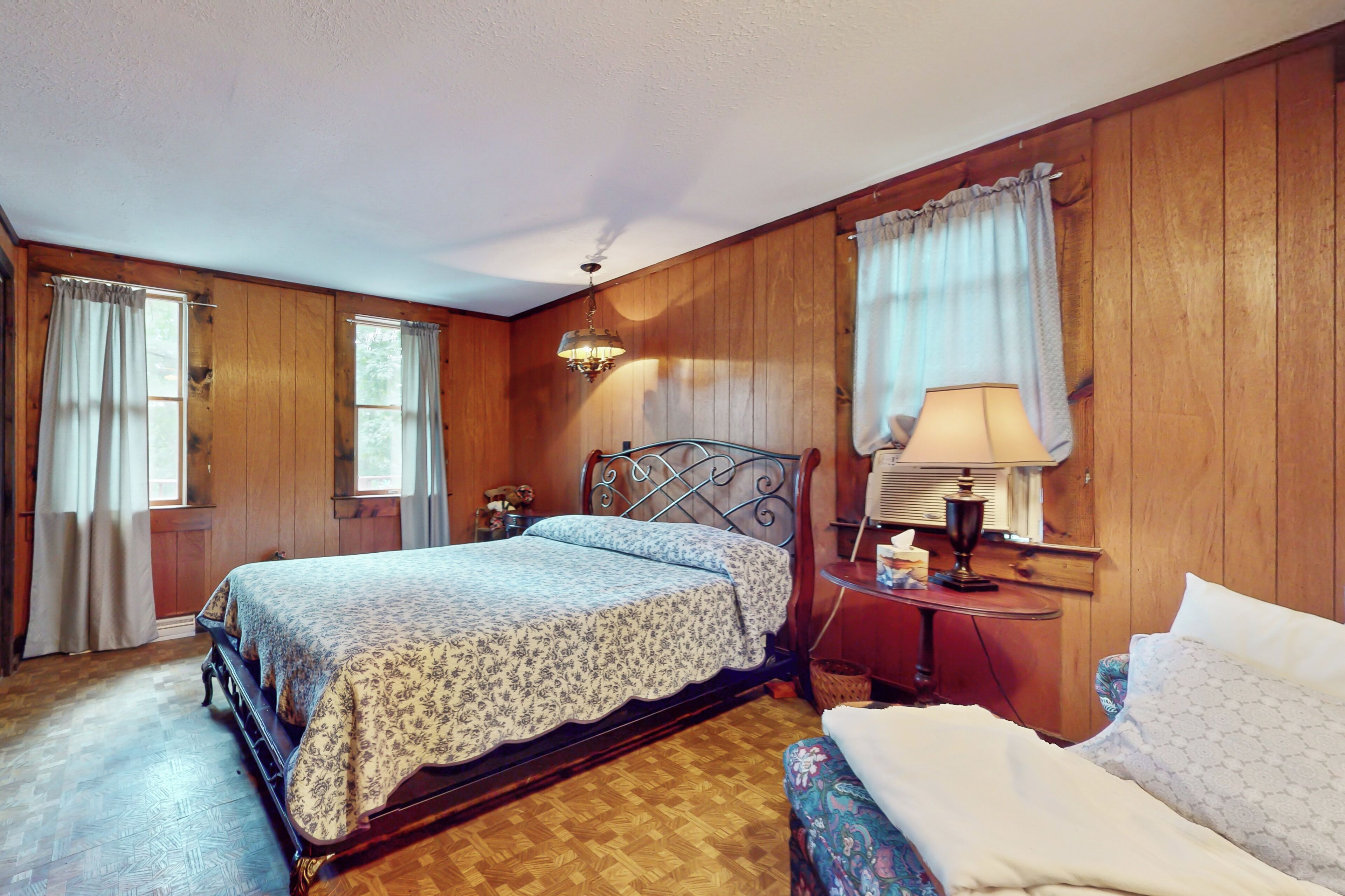 Une chambre à coucher aux murs lambrissés, avec un lit, une table de chevet, une lampe et une chaise.