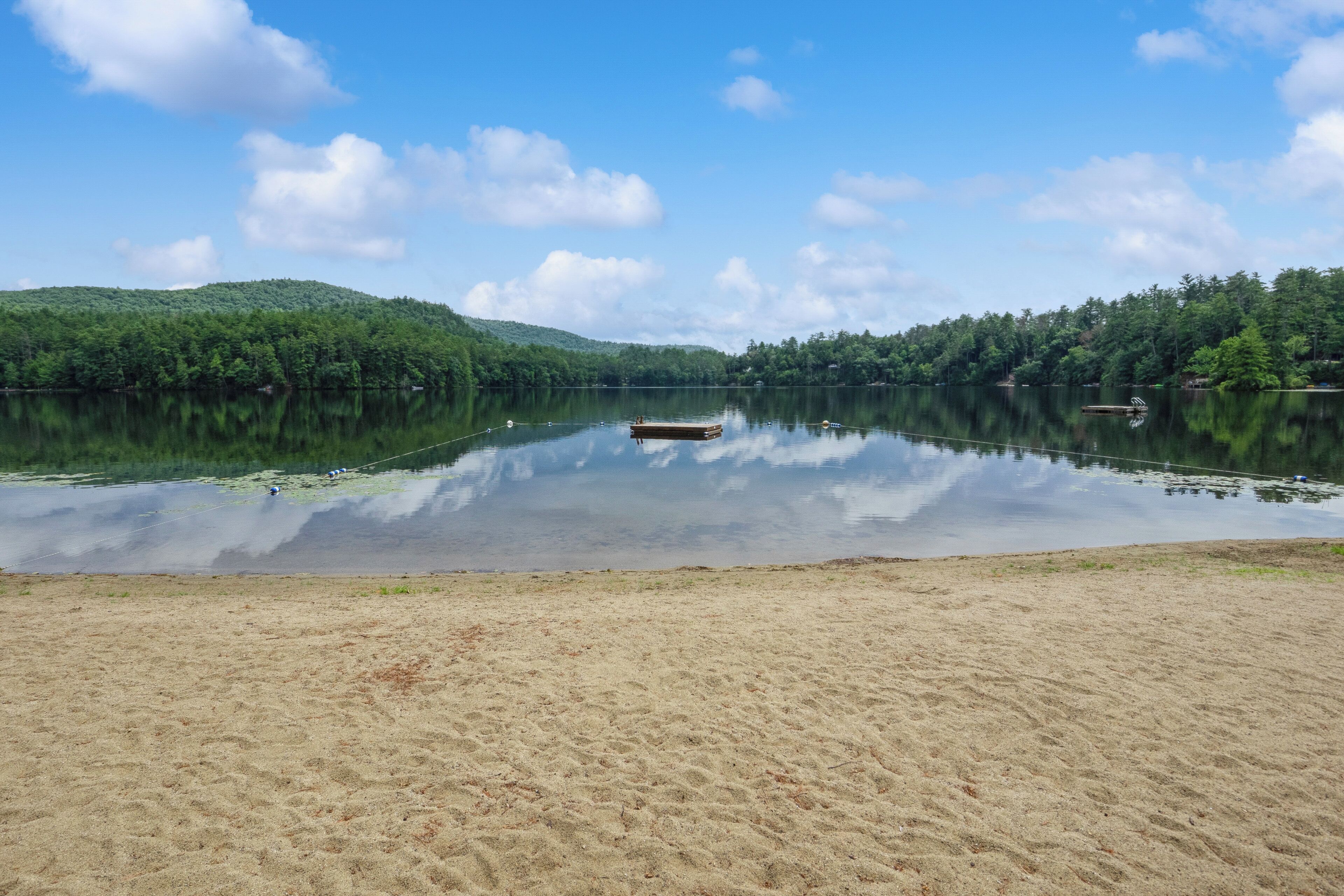 Ein ruhiger See mit einem Sandstrand und einem Steg.