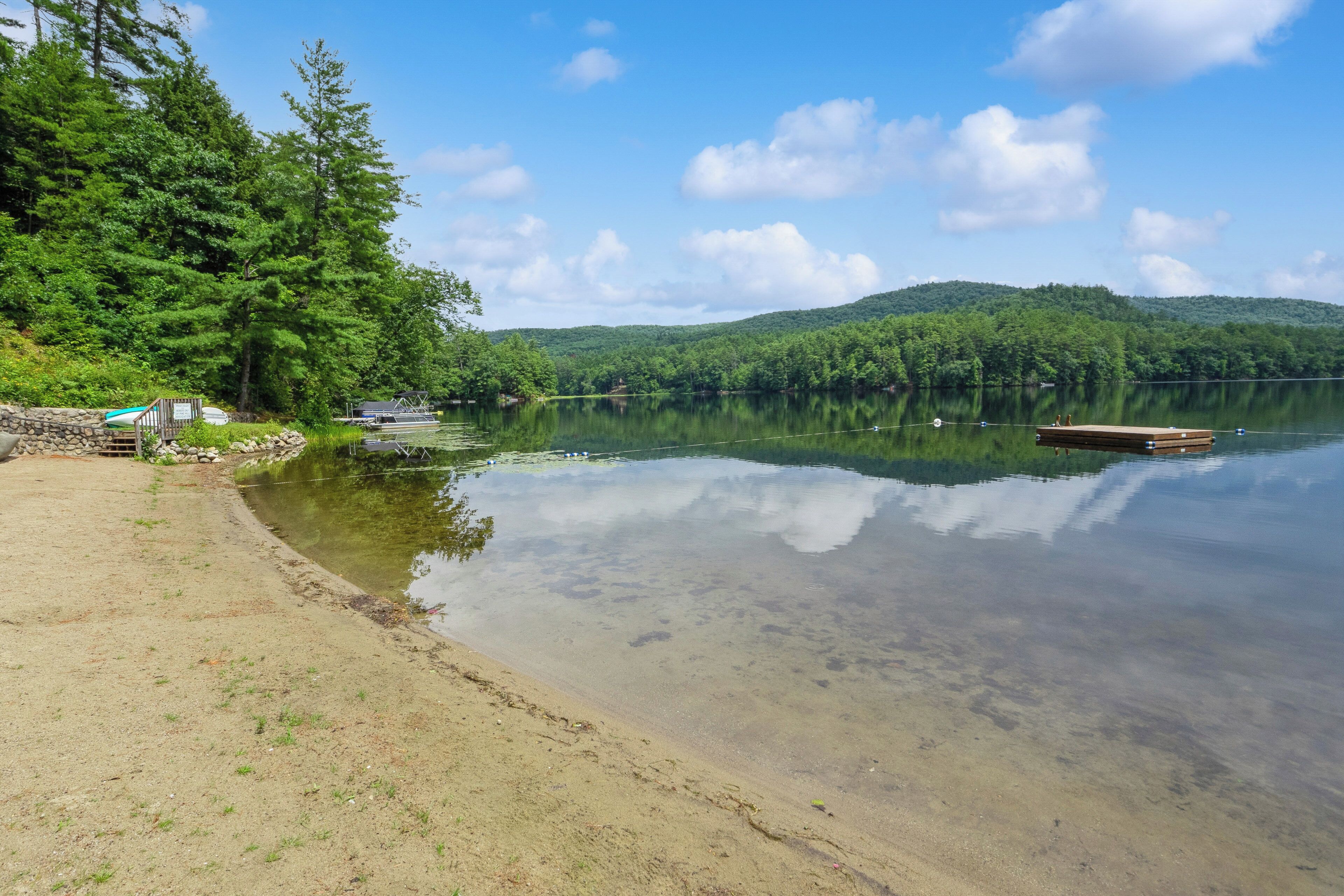A lakeside area with a dock, clear water, and surrounding forest.
