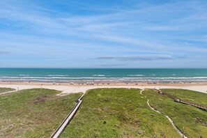 A coastal landscape with a beach, grassy areas, and a wooden boardwalk. - Beachfront Corner 3br: Suntide III - Unit 910 (New Haven)