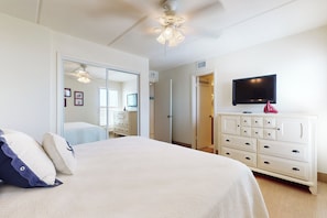 A bedroom with a bed, dresser, TV, and a ceiling fan. - Beachfront Corner 3br: Suntide III - Unit 910 (New Haven)