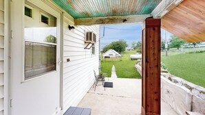 A covered porch with a wooden bench, a small table, and a chair. - Historic Family Farmhouse w/ Yard in Darlington! (Darlington)