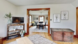 A living room with a TV, wooden furniture, a dining area, and a vintage chest. - Historic Family Farmhouse w/ Yard in Darlington! (Darlington)