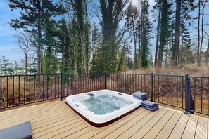 A hot tub on a wooden deck with a metal railing, surrounded by tall trees. - Hot Tub & Mtn Views: Lummi Island Home Near Beach (Lummi Island)