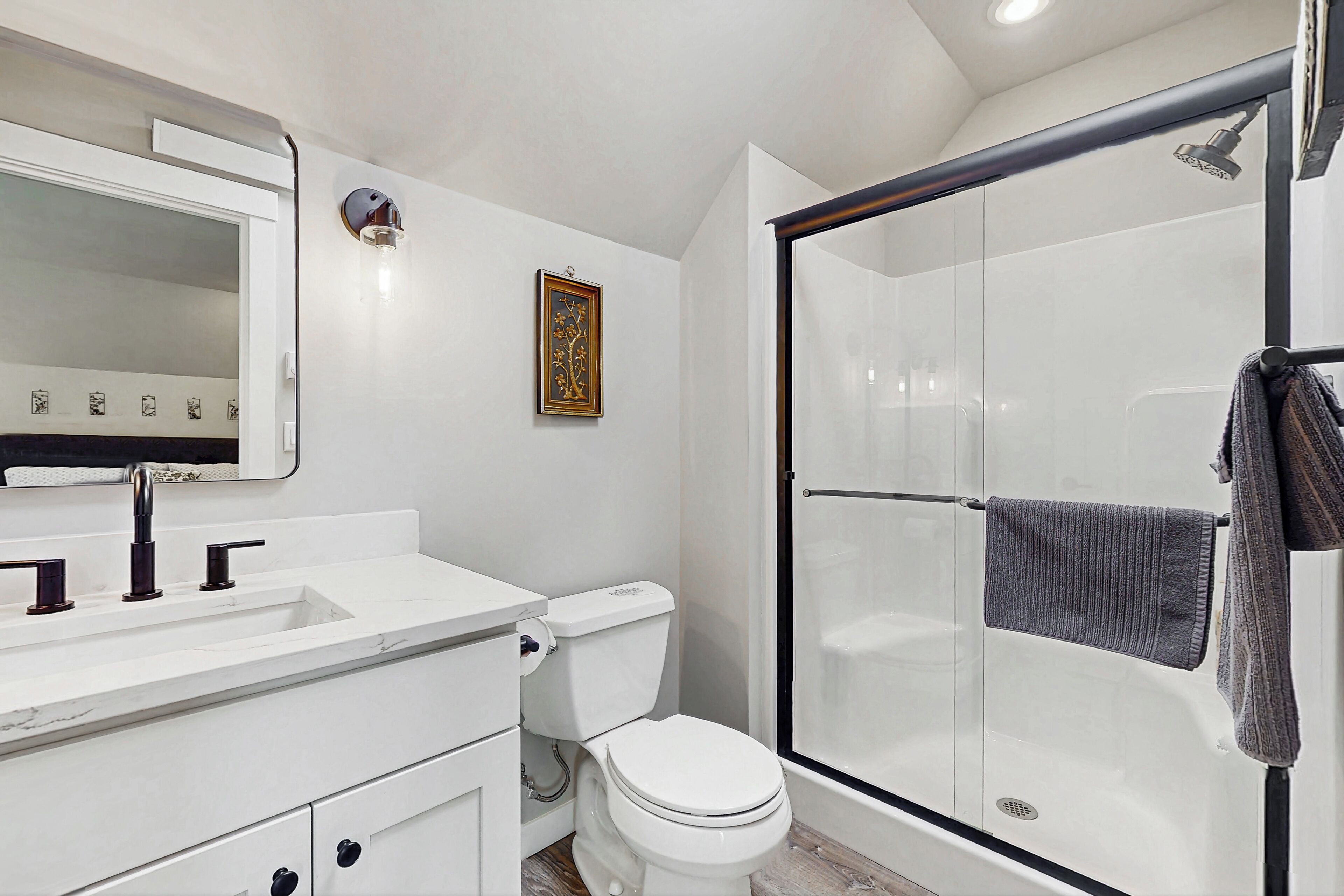 Une salle de bain moderne avec un lavabo blanc, des toilettes et une douche à parois de verre.