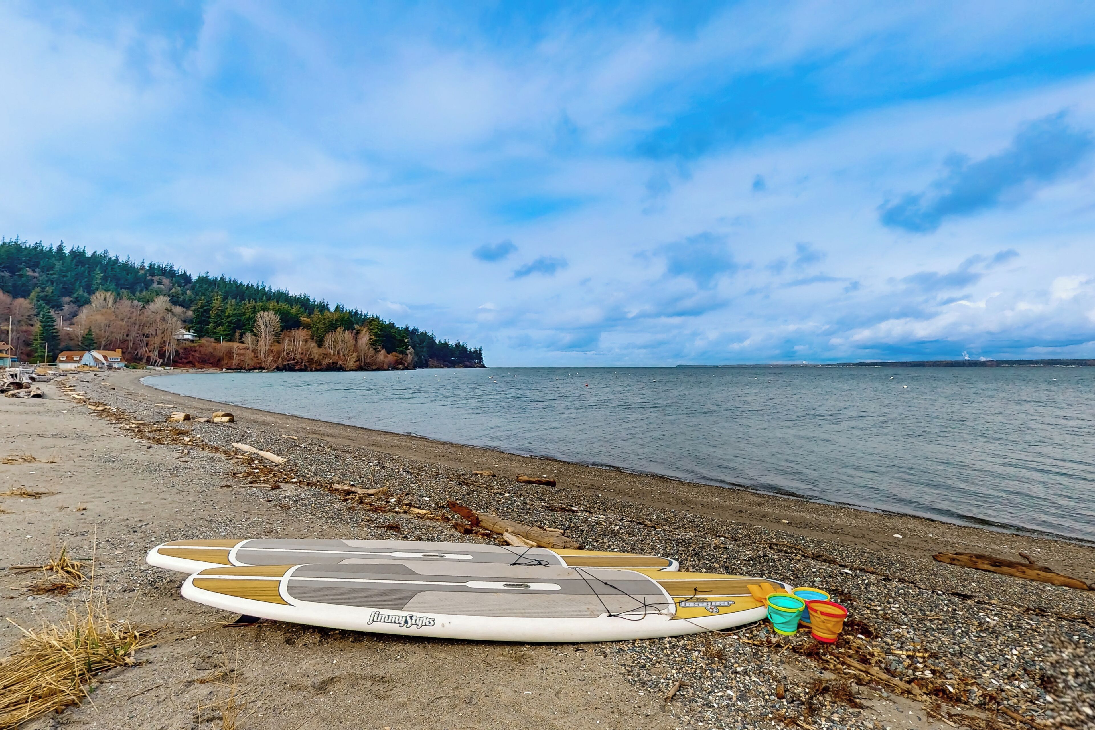 Une plage avec des planches de surf et des seaux sur le rivage.