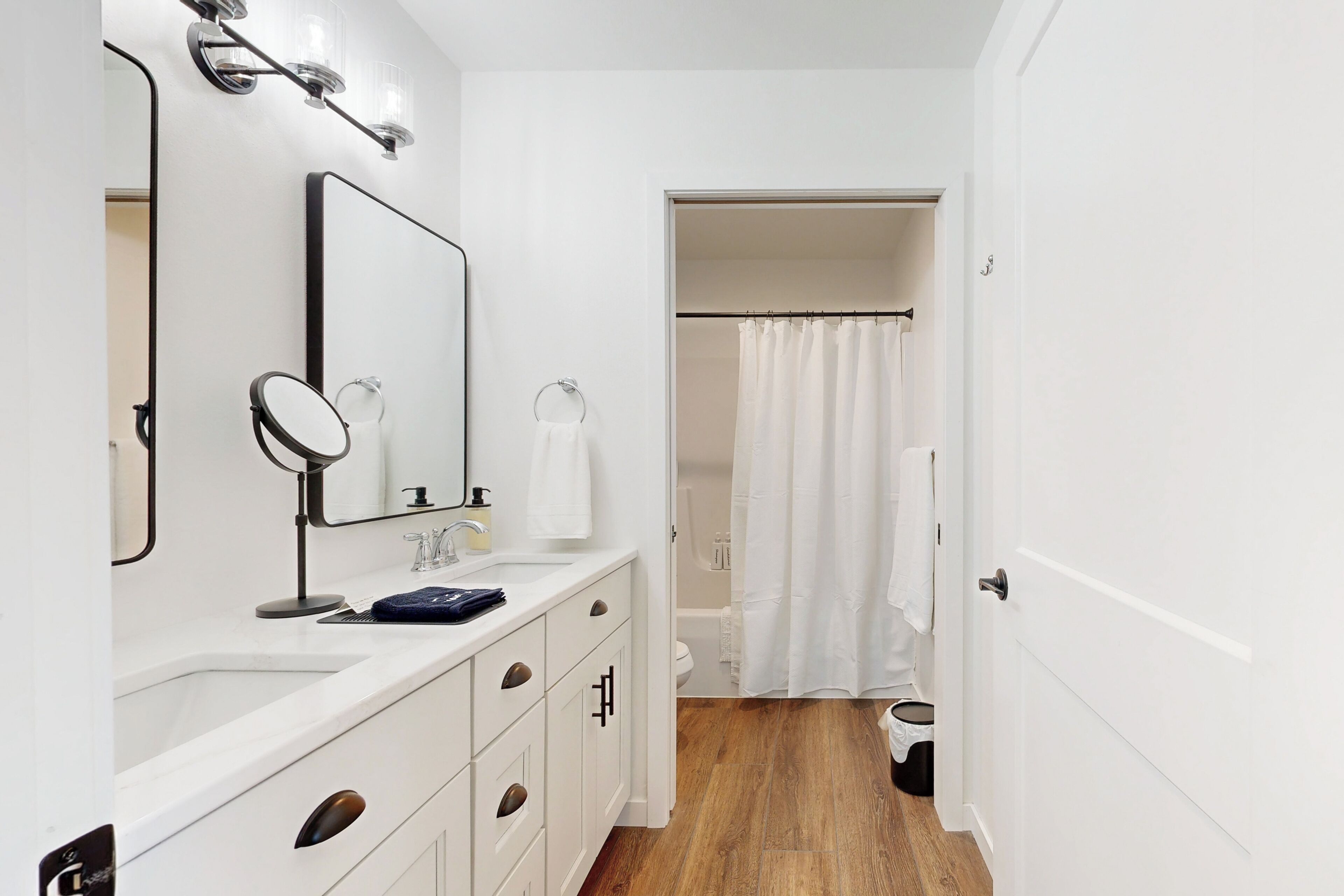 A modern bathroom with a white vanity, a mirror, a sink, and a shower curtain.