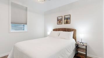 A bedroom with a large bed, a bedside table with a lamp, and two framed pictures on the wall.