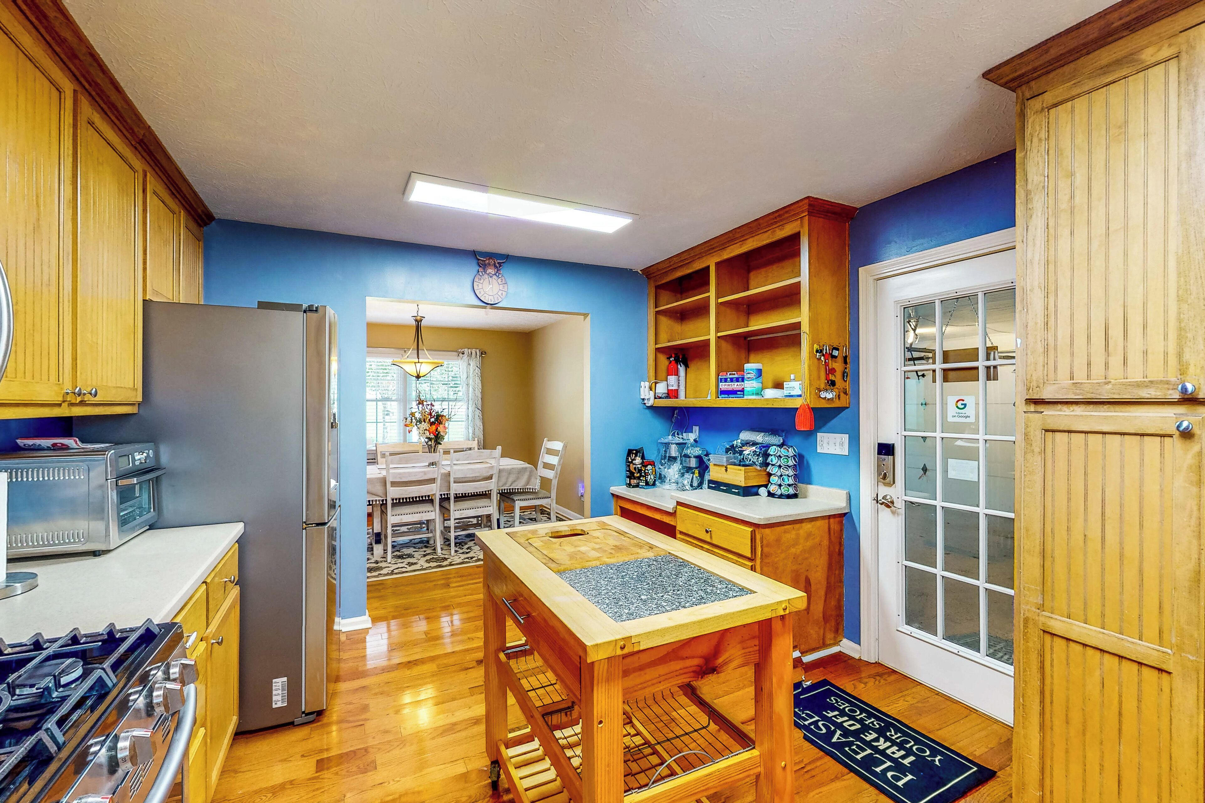 A kitchen with wooden cabinets, a refrigerator, a stove, and a dining area with a table and chairs.