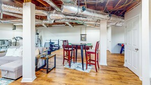 Une pièce spacieuse dotée d’un plancher en bois, d’une table à manger avec des chaises, d’un canapé et d’un plafond laissant apparaître les conduits.