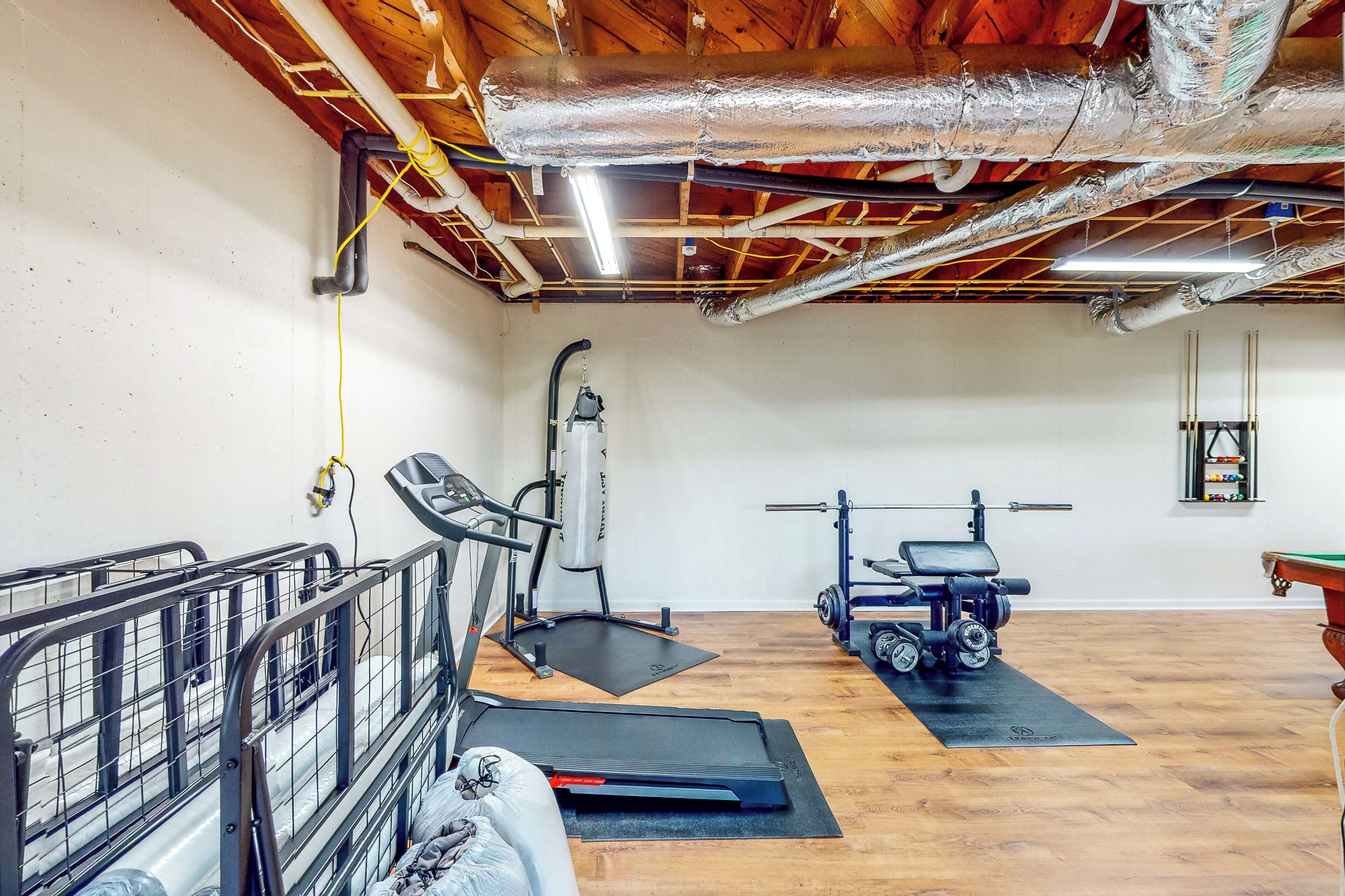 A home gym with exercise equipment, a wooden floor, and exposed ceiling beams.