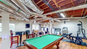 Une pièce spacieuse équipée d’une table de billard, d’appareils de musculation et d’un coin repas.