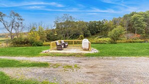 A covered outdoor seating area with chairs and a table, surrounded by a wooden deck and a grassy field. - Countryside Couples Retreat! Gateway to Corning (Cameron Mills)