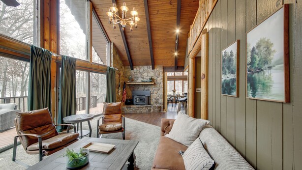 Una sala de estar acogedora con chimenea de piedra, muebles de cuero y amplios ventanales.
