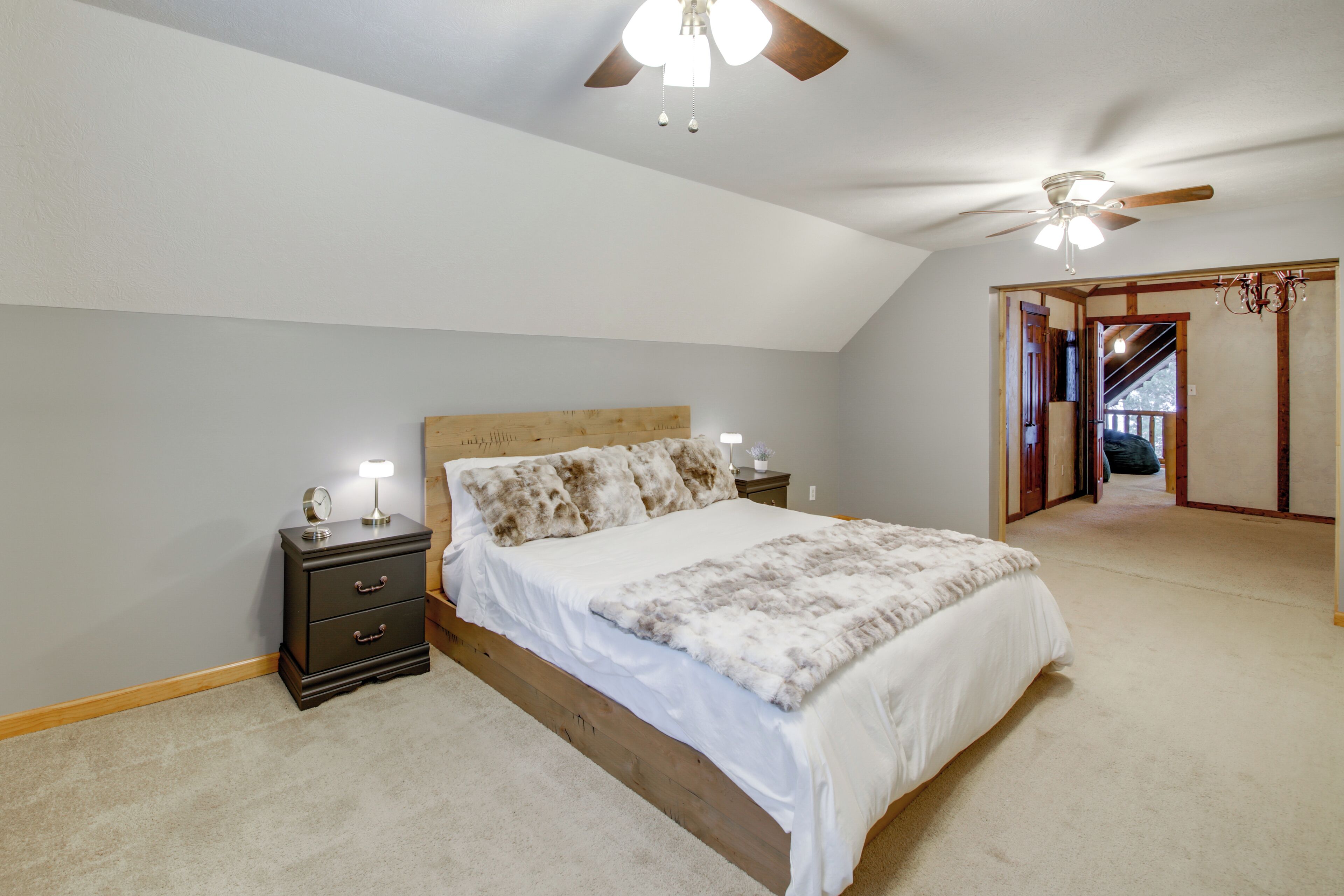 A bedroom with a wooden bed, a nightstand, a ceiling fan, and a walk-in closet.