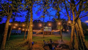 A cabin with a deck and a fire pit surrounded by trees. - River-view Home w/ Fire Pit & Grill! (Cedar Bluff)