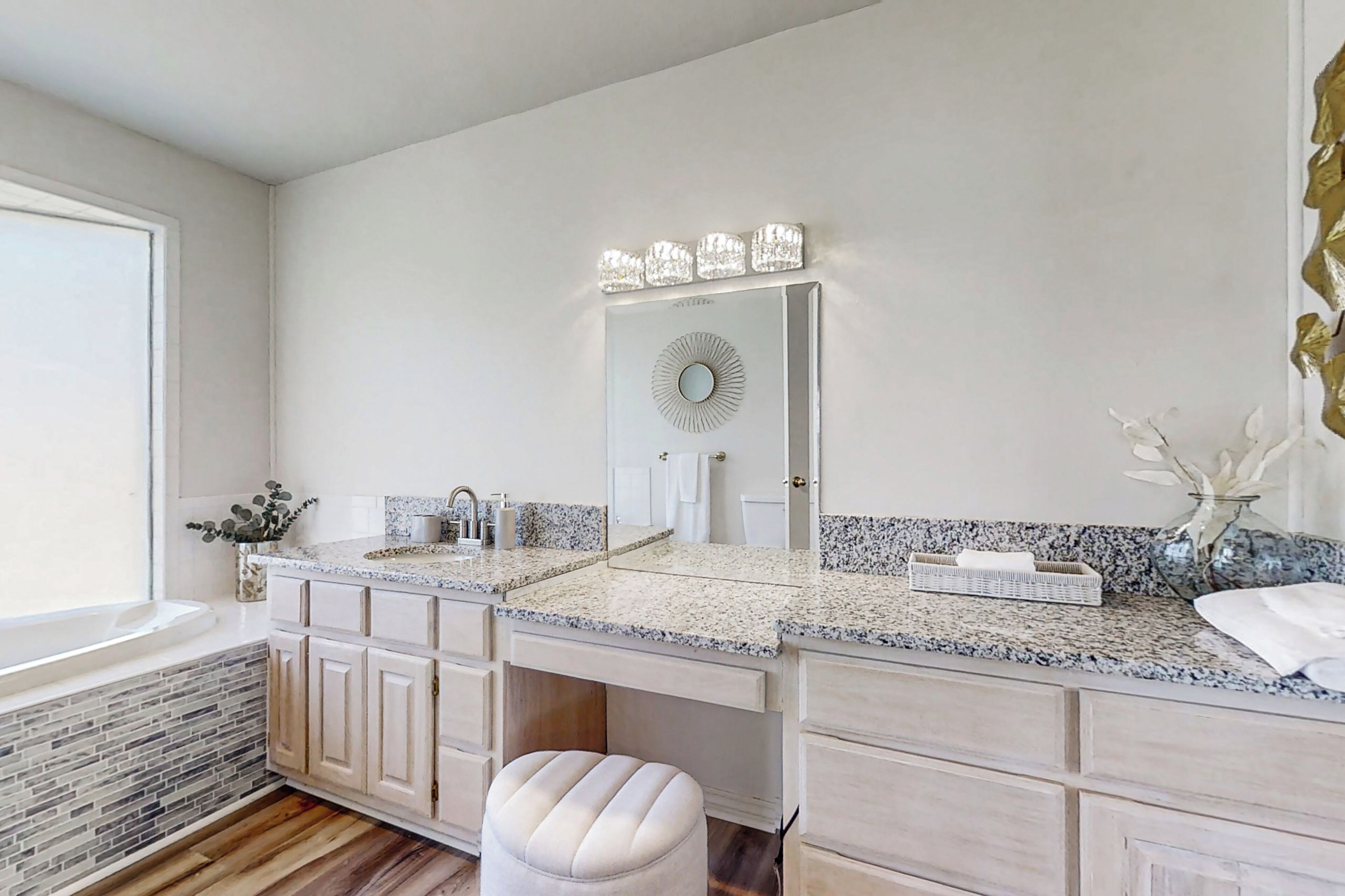 A bathroom with a double vanity, a large mirror, and a bathtub.