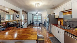 A kitchen with a wooden island, stainless steel appliances, and a dining area with a table and chairs. - Serene 3BR Farmhouse w/ Deck & Pond (Wilmer)