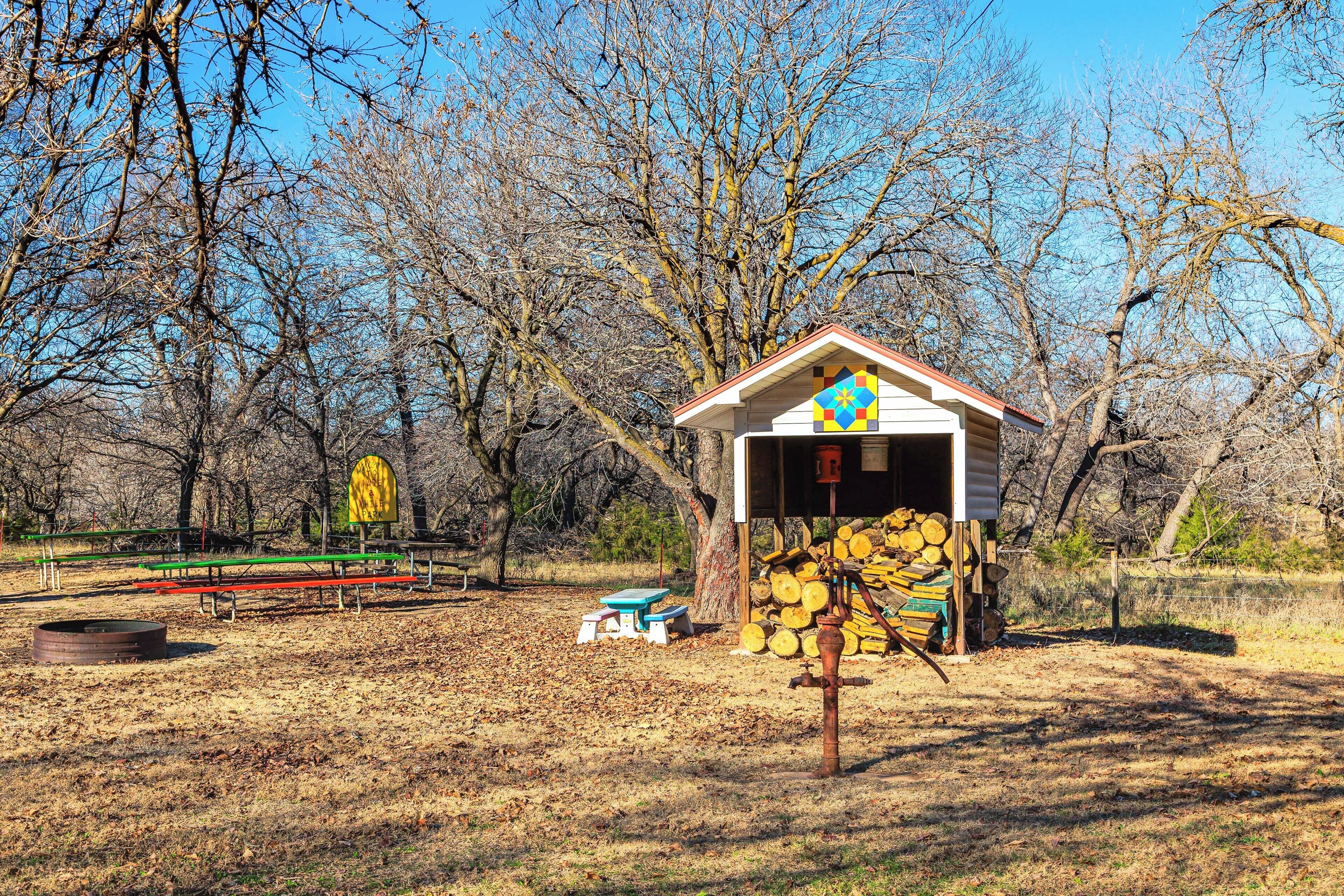 Une cabane en bois rustique, dotée d’une cheminée, entourée d’arbres et agrémentée d’une table de pique-nique.