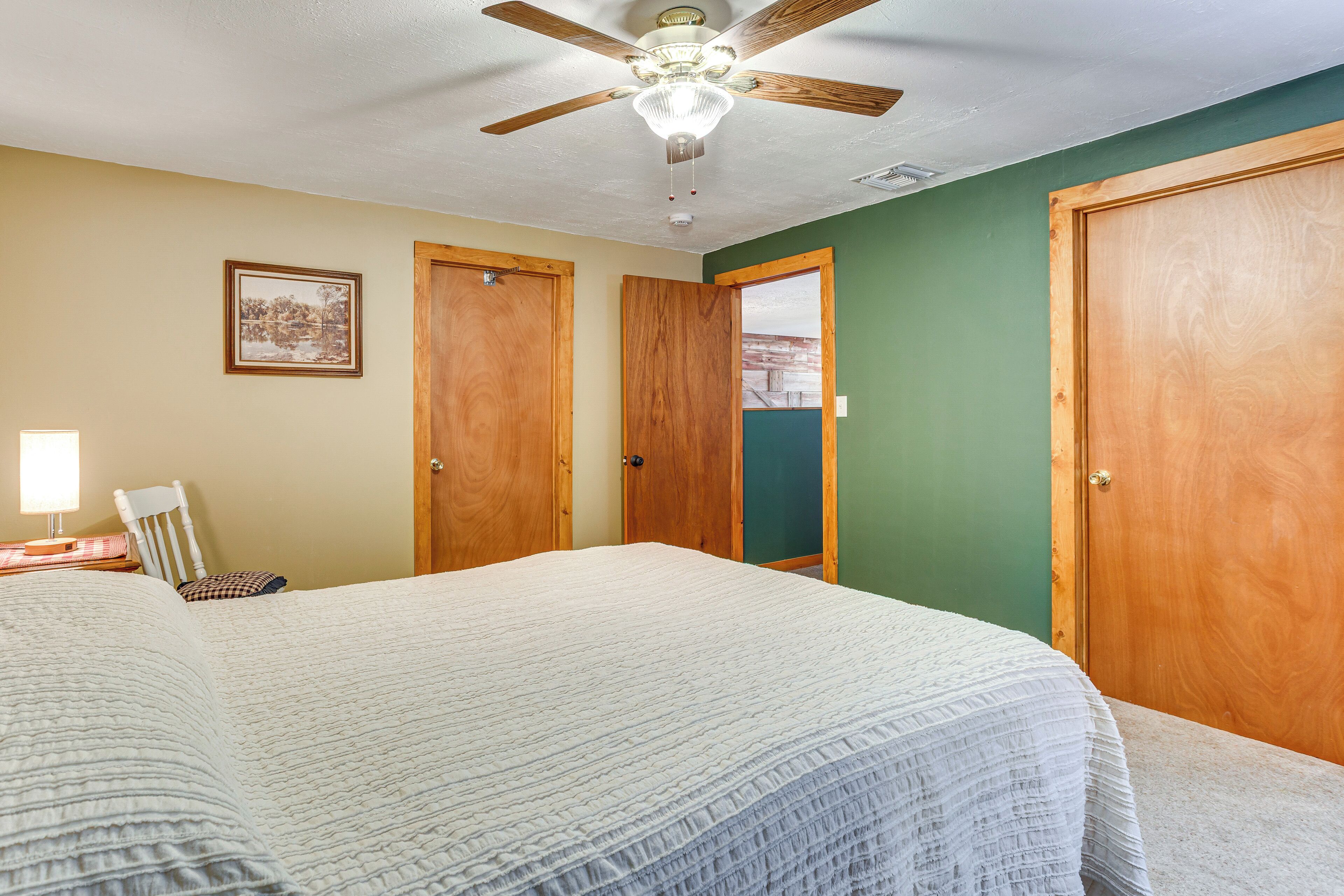 Une chambre à coucher avec un lit, un ventilateur de plafond et des portes en bois.