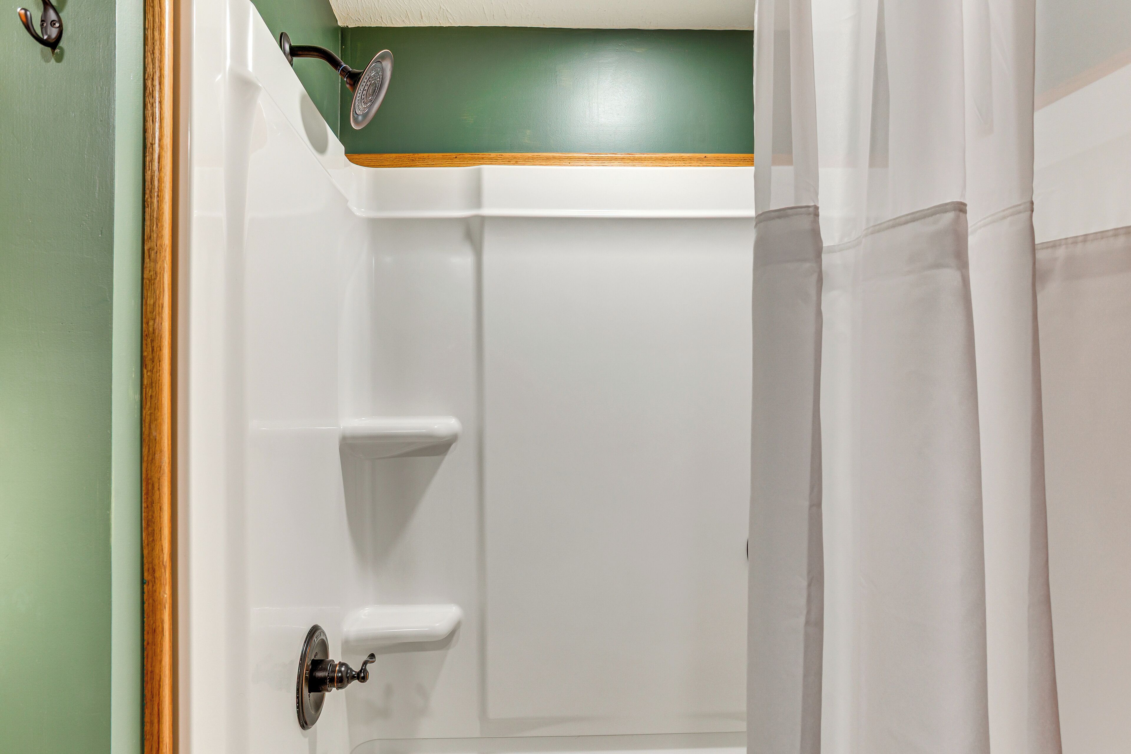 A bathroom with a shower, a towel rack, and a door with a handle.