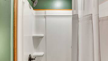 A bathroom with a shower, a towel rack, and a door with a handle.